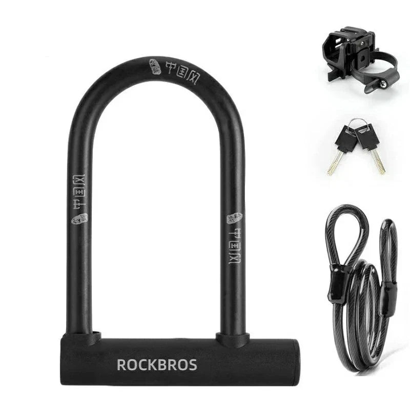 Black U-shaped bicycle lock with a heavy-duty base, shown with two keys and included accessories on a plain white background. The brand name ROCKBROS is clearly visible on the base and lock body. #Color_Lock+Cable