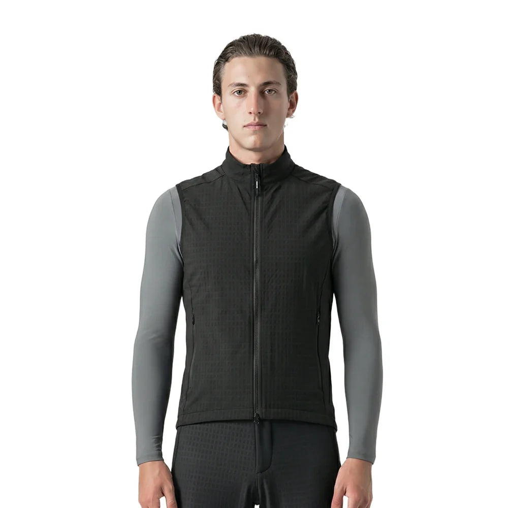 A man wearing a black zip-up athletic vest over gray long-sleeve compression sleeves, photographed against a plain white studio background.