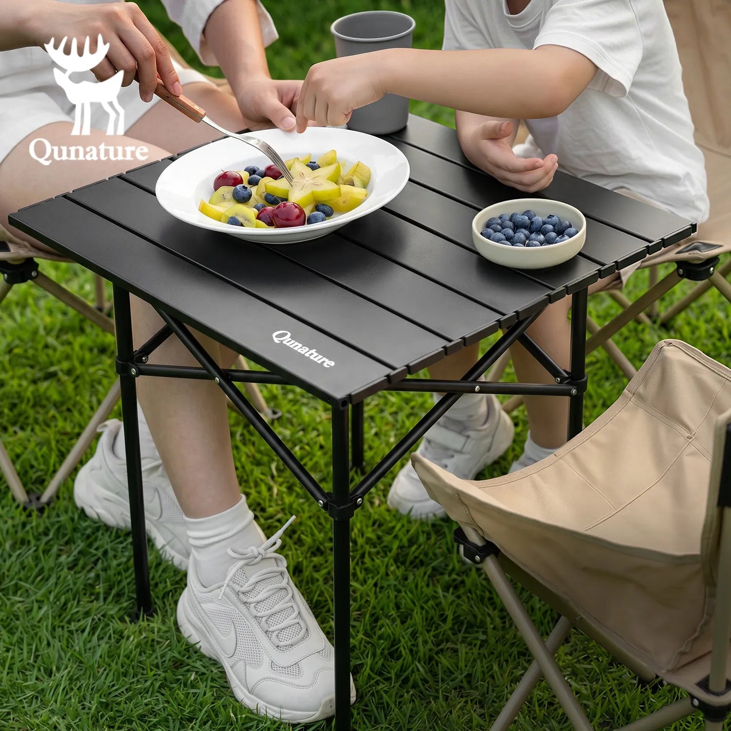 People eating fruit at a Qunature folding table outdoors