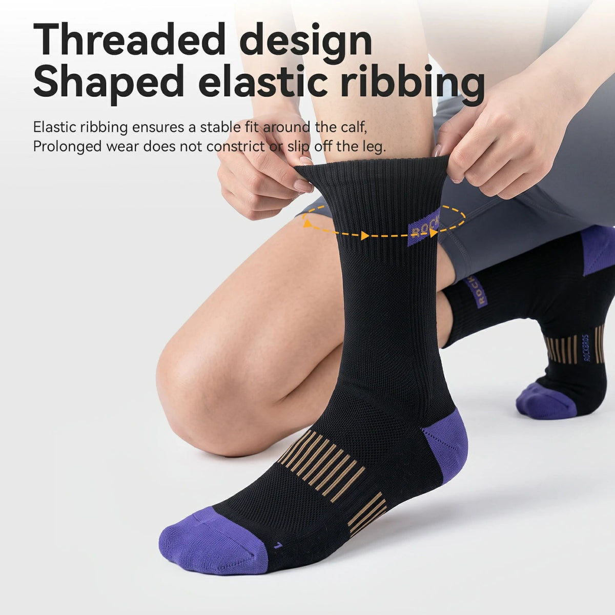 A person kneeling while putting on a black athletic sock with purple toe and heel accents and tan striped detail. The image includes marketing text about threaded design and shaped elastic ribbing, with a second sock visible in the background.