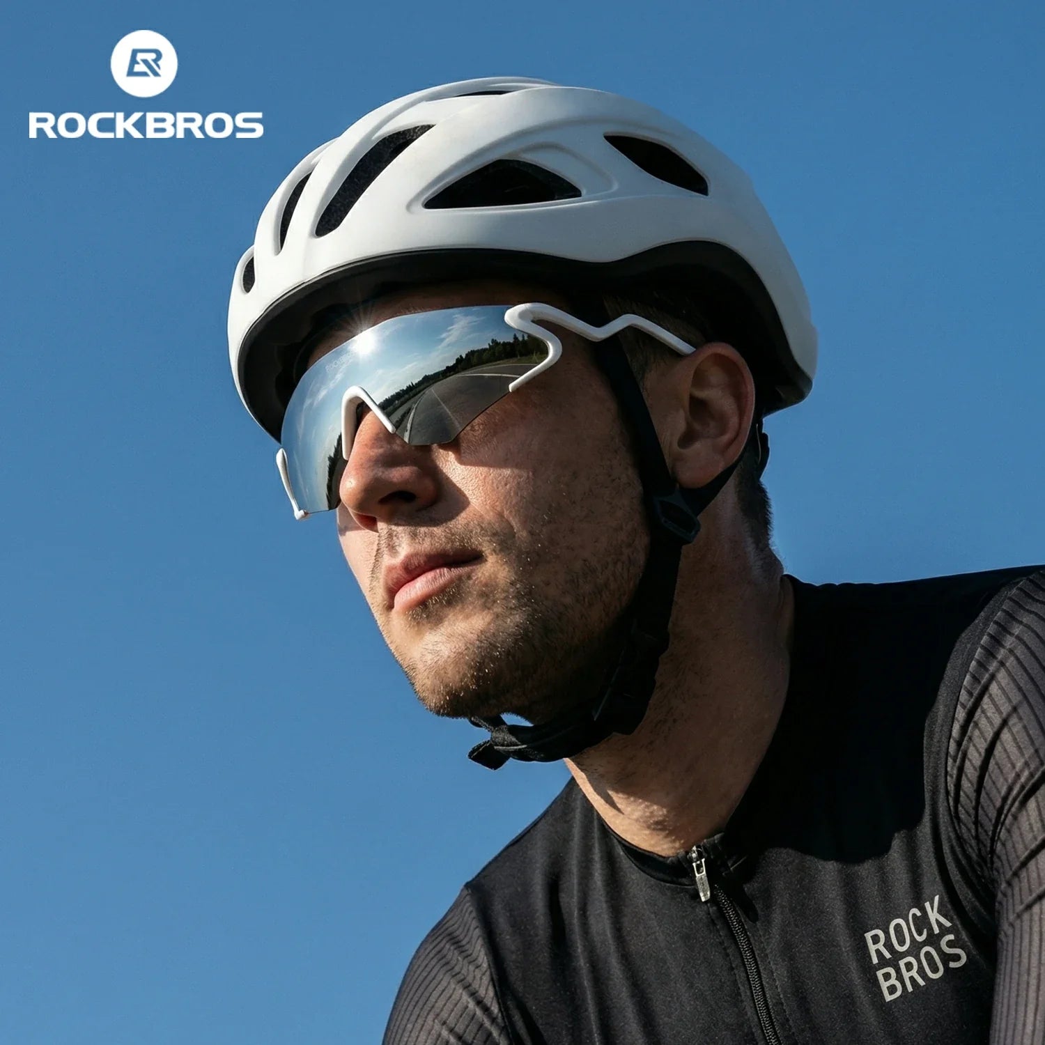 Person wearing a white helmet and sunglasses with a clear blue sky background, featuring the RockBros brand. #Color_White
