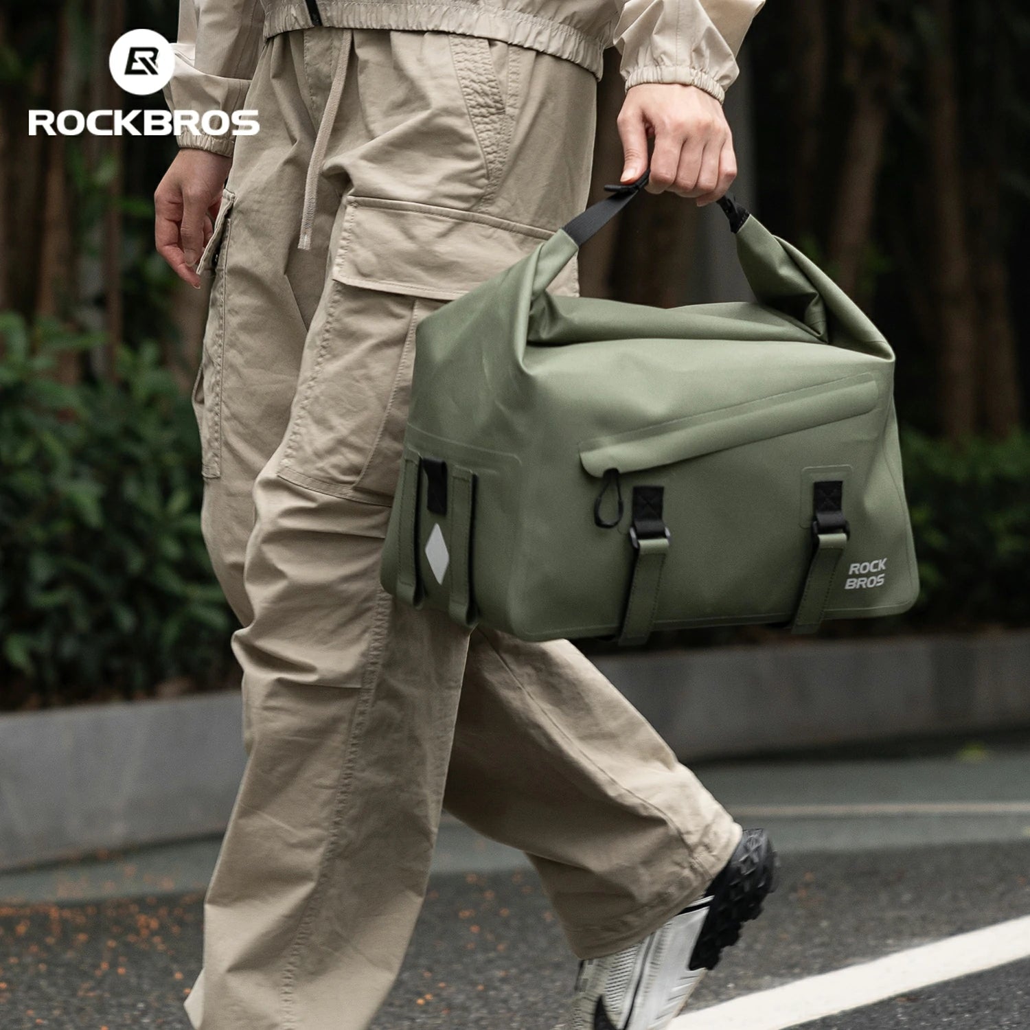 Person walking outdoors carrying a green bag with 'RockBros' branding. #color_green