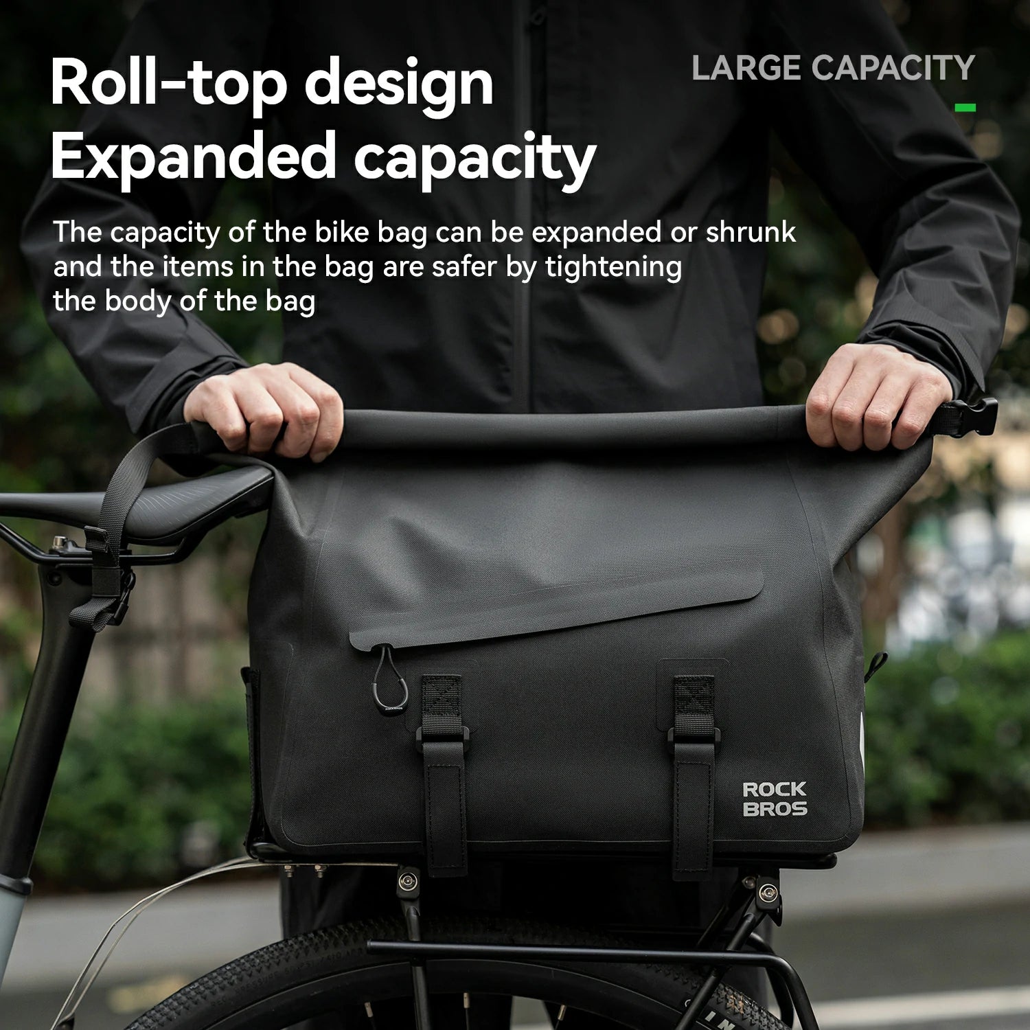 Person holding a black bike bag with text highlighting roll-top design and expanded capacity.