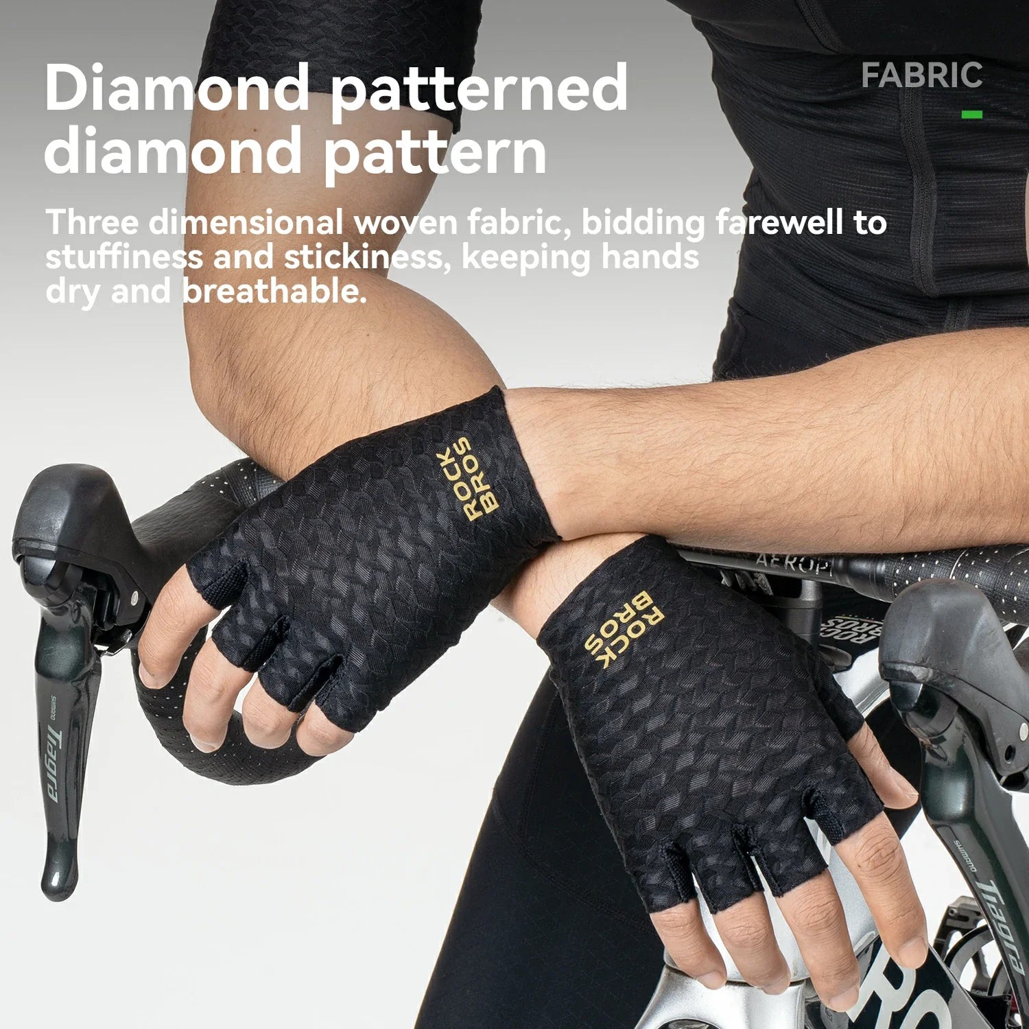 A close-up of a cyclist's hands wearing black Rock Bros fingerless cycling gloves with a diamond pattern and gold lettering, holding bicycle handlebars. White text on the left describes the diamond patterned fabric.