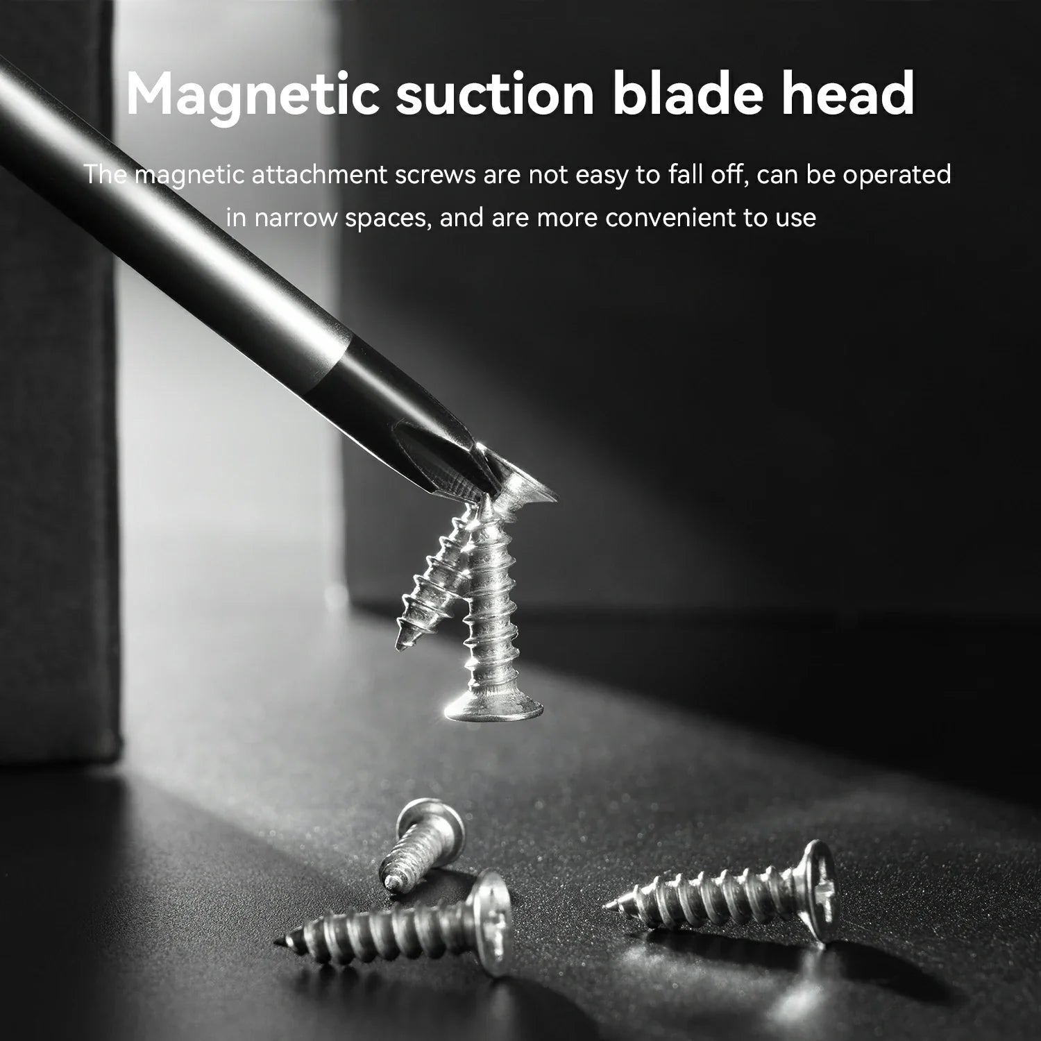 A close-up product demonstration showing a magnetic suction blade head attached to a screwdriver bit, holding a metal screw against a dark surface. White text at the top reads 'Magnetic suction blade head' with additional descriptive copy below, and several loose screws are scattered on the surface.
