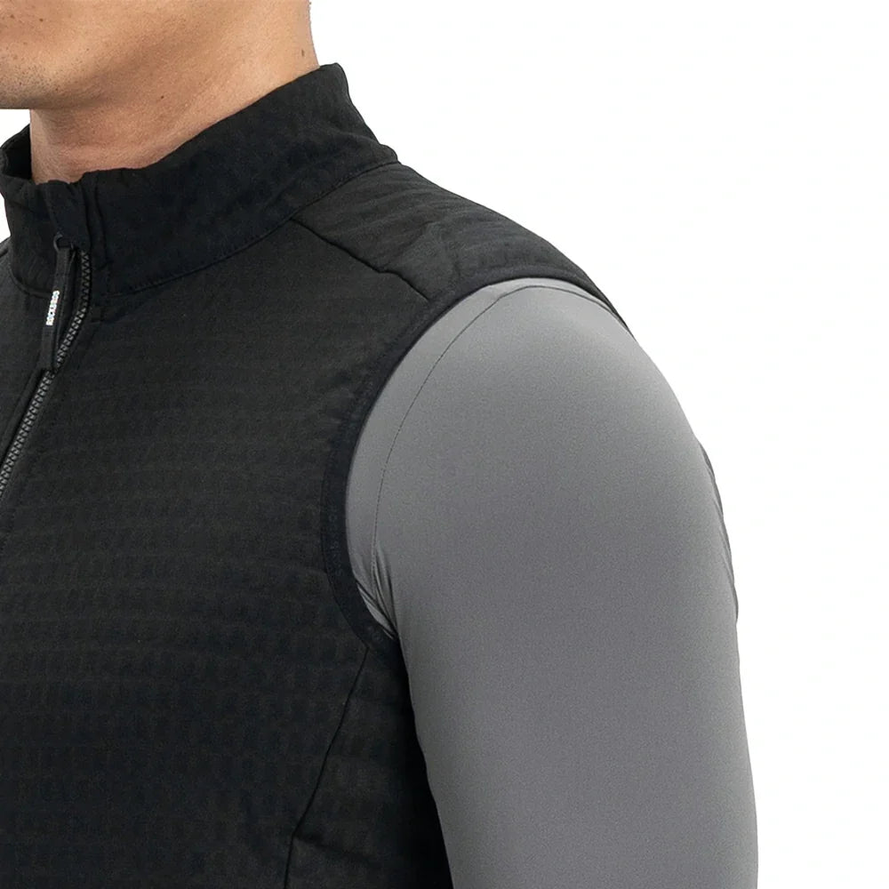 Close-up of a person wearing a black sleeveless zip-front vest over a fitted gray long-sleeve base layer, shown against a plain white background.