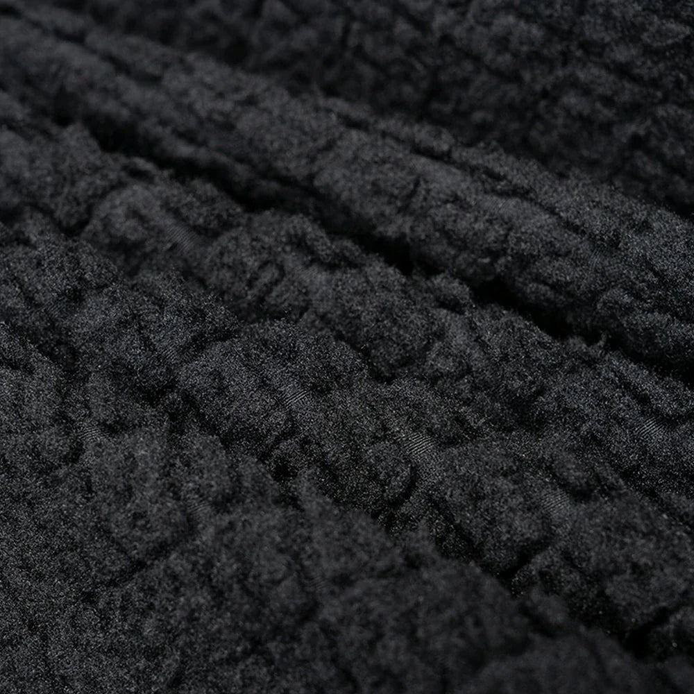 Close-up of a dark charcoal gray or black textured fabric with a ribbed, quilted, or bouclé-like surface.