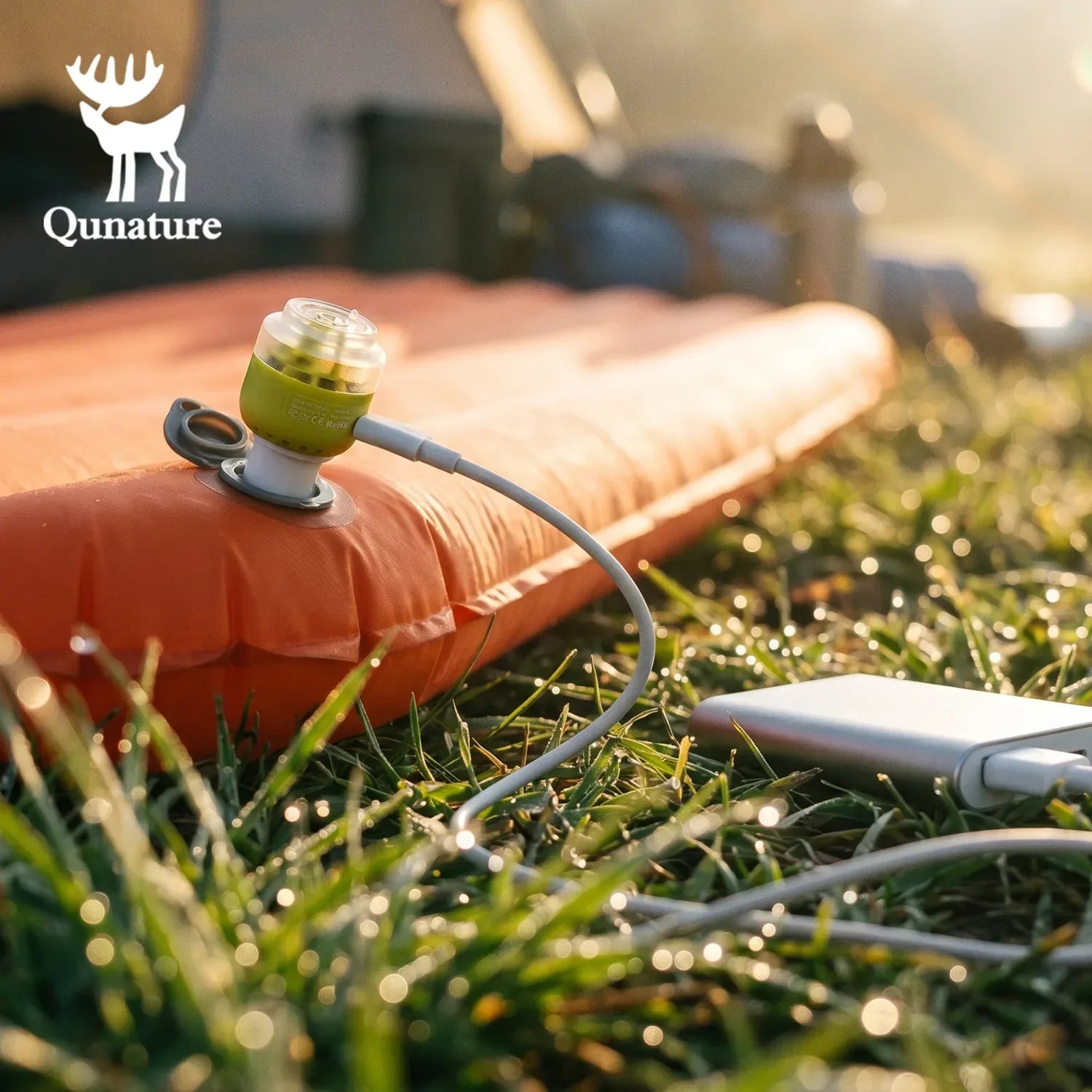 Orange inflatable camping mattress with pump on grass, Qunature brand visible