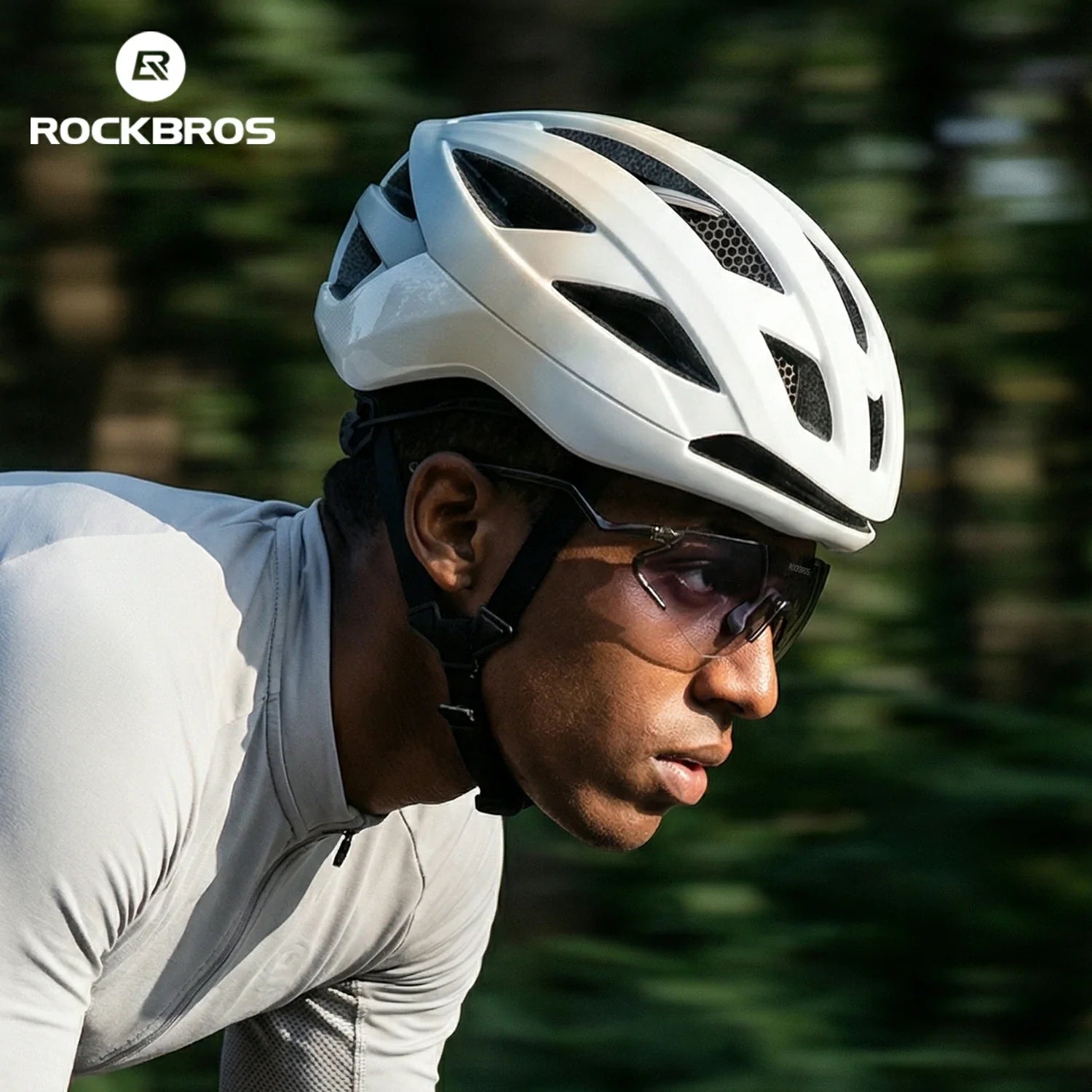 Person wearing a white helmet and sunglasses with a blurred green background, featuring the RockBros brand. #Color_Green